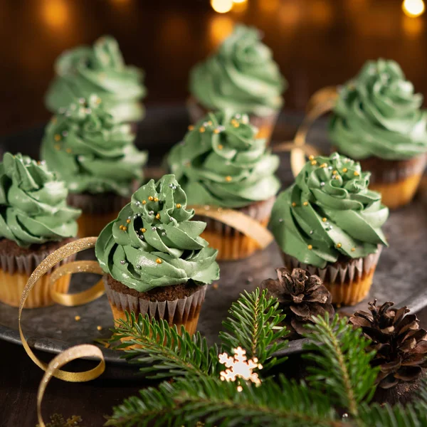 Árbol de Navidad cupcakes postre dulce con salpicaduras de oro sobre fondo de madera con luces de guirnalda bokeh. Primer plano. Navidad y año nuevo vacaciones concepto de fondo . — Foto de Stock