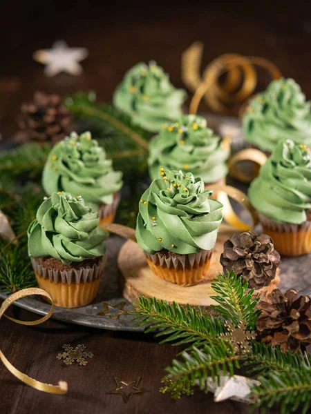 Árbol de Navidad cupcakes postre dulce con salpicaduras de oro sobre fondo de madera con luces de guirnalda bokeh. Primer plano. Navidad y año nuevo vacaciones concepto de fondo . — Foto de Stock