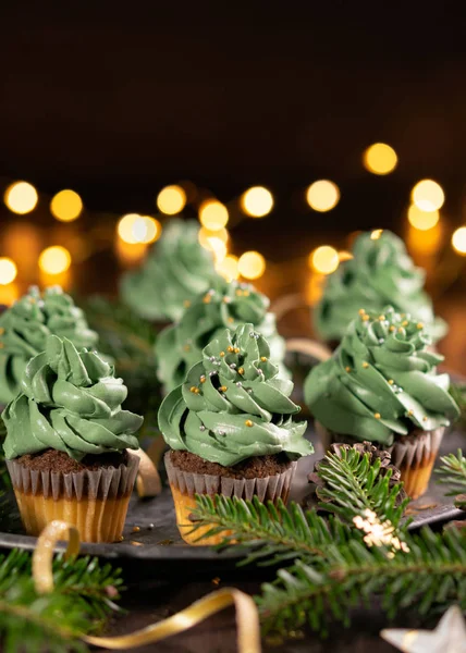 Pastel de Navidad verde con stsprinkles sobre fondo de madera con luces de guirnalda bokeh, espacio de copia. De cerca. Navidad y año nuevo vacaciones concepto de fondo . — Foto de Stock