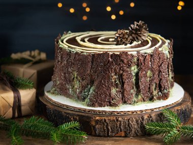 Bulanık yılbaşı ışıklarıyla çikolatalı ağaç kütüğü pastası. Noel ve yeni yıl tatili konsepti. Boşluğu kopyala.