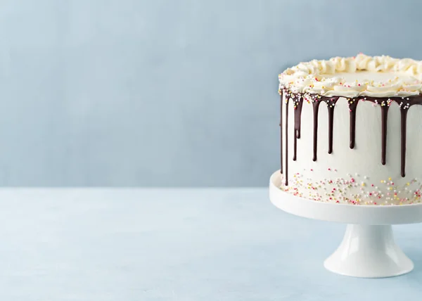 誕生日パーティーの装飾が施された白い背景バナーにチョコレートガナッシュとスプリンクル付きのドリップケーキ コピースペース お祝いのコンセプト トレンディーなドリップケーキ 選択的焦点 — ストック写真