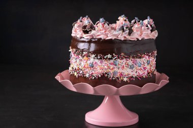 Çikolata ganache ve pasta standında pembe renk dekoru olan modaya uygun fay hattı pastası, fotokopi alanı olan koyu arkaplan. Doğum günü kutlaması, romantik konsept. Sevgililer Günü, Anneler Günü.