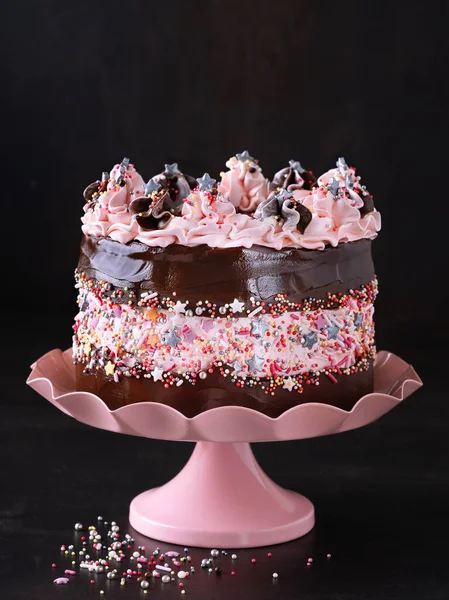ケーキスタンドのスプリンクルチョコレートガナッシュとピンクの色の装飾で飾られた誕生日ケーキ コピースペースの暗い背景 お祝いの概念 バレンタイン 母の日 — ストック写真
