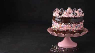 Koyu kahverengi arka plan pankartıyla süslenmiş pembe tereyağlı doğum günü pastası. Uzayı kopyala Kutlama konsepti, Moda Keki.