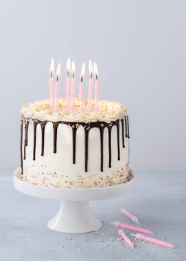 Beyaz doğum günü pastası, çikolata kreması ve açık mavi arkaplanlı ve kopyalanmış mumlar. Moda parti dekorasyonu pasta konsepti.