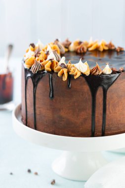 Koyu çikolata ve açık mavi arka planda çikolata jöleli fıstık keki. Mesaj için yer var. Tatlı yemek. Tatlı tatlı. Modaya uygun damlayan pasta..