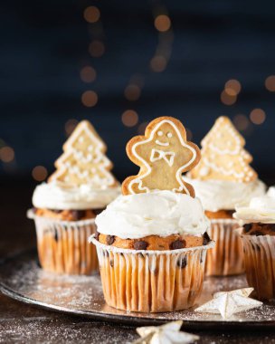 Spice cupcakes with cream cheese frosting decorated with a gingerbread cookies. Selective focus, copy space, close up. clipart
