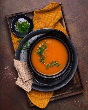 Kara taş masada maydanozlu balkabağı çorbası ve tohum krakerleri, yakın plan, üst manzara. Geleneksel sonbahar ve kış yemekleri.