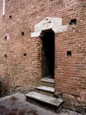 access door in the brick wall of the tower. Siena. Italy
