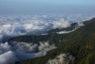 Güneş doğduktan sonra bulutlarla çevrili bir dağ