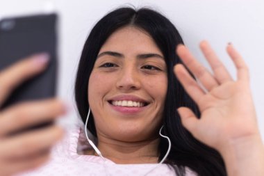 Coronavirus karantinası nedeniyle kadın cep telefonunu evde video görüşmesi yapmak için kullanıyor.