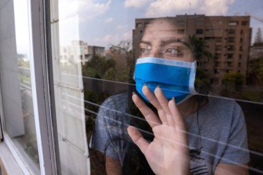 Coronavirus karantinası tarafından hapsedilirken kadın evinin penceresinden izliyor..