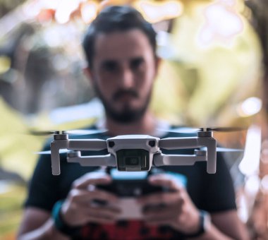 Mavic Mini İHA 'sının ön kapanışı uzaktan kumandayla onu kontrol eden birinin üzerinde uçuyor.