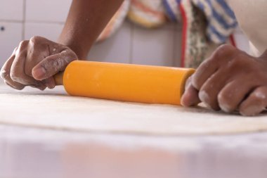 Masada yoğururken merdane kullanan birinin ayrıntıları.