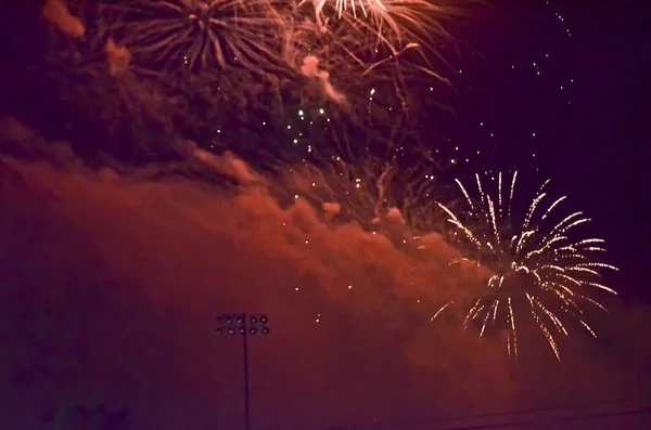 Fireworks Exploding with a Cloud of Red Smoke above a Dark Stadium Light
