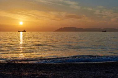 Güneş geminin üzerinde, gün batımı denizin üzerinde.