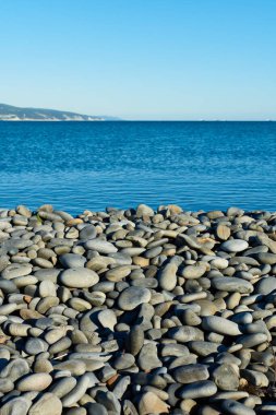Sahildeki taşlar dağlar ve denizin arka planına karşı.