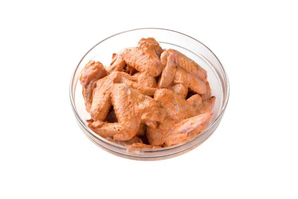 Marinated chicken wings in a glass bowl. Glass dish with pickled wings on a white background.