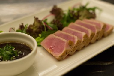 Yanında yeşil salata ve sos ile kurutulmuş ton balığı.