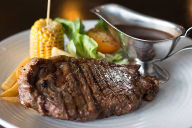 Patates kızartması, fırında mısır ve karabiber sosuyla birlikte ızgara sığır filetosu.