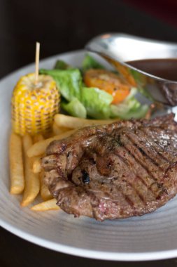 Patates kızartması, fırında mısır ve karabiber sosuyla birlikte ızgara sığır filetosu.