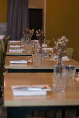 Vazolarla, kurutulmuş çiçeklerle, peçetelerle ve çatal bıçaklarla dolu güzel bir masa.