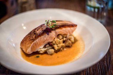 Tavada Norveç somonu, ezilmiş patates, domates ve kabuklu deniz hayvanı çorbası.