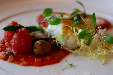 Tavada kızarmış morina balığı, domates püresi, zeytin ve bitki salatası.