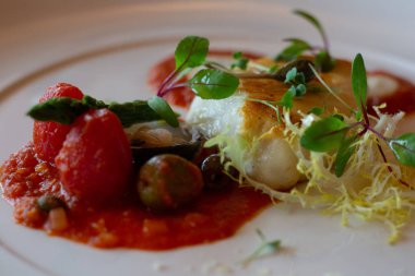 Tavada kızarmış morina balığı, domates püresi, zeytin ve bitki salatası.