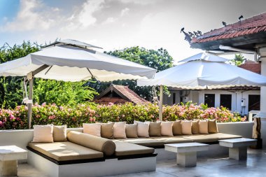 Bahçede yastıklı ve ağaçlı olarak otururlar.