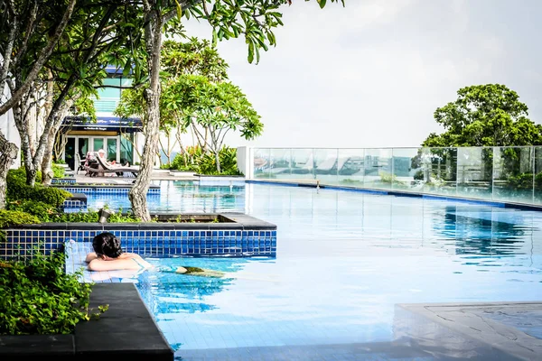 Piscina panoramica a sfioro con sedie a sdraio e alberi — Foto Stock