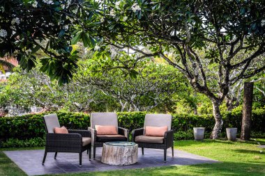 Bahçede yastıklı ve ağaçlı olarak otururlar.