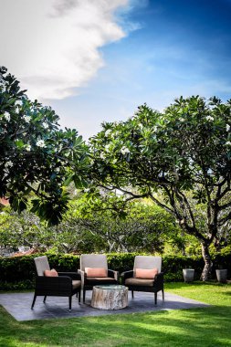 Bahçede yastıklı ve ağaçlı olarak otururlar.