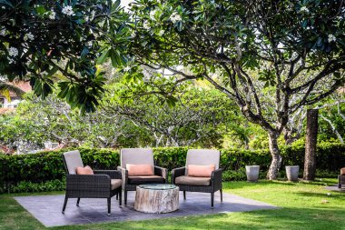 Bahçede yastıklı ve ağaçlı olarak otururlar.