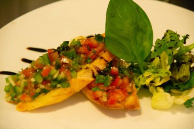 Mutfakta üniformalı bir şef buchetta ve chikcen piccata hazırlıyor.