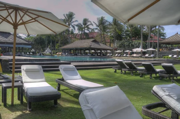 Tumbonas reclinables bajo grandes sombrillas junto a la piscina — Foto de Stock