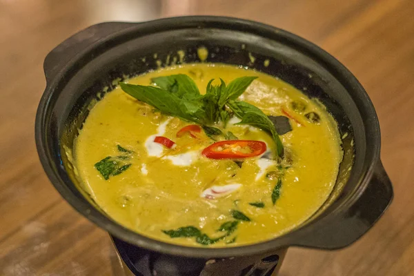 Grünes thailändisches Curry mit Chili und thailändischem Basilikum in einer Schüssel serviert, die durch ein Teelicht warm gehalten wird — Stockfoto