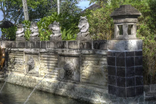 Traditional balinese architecture and statues and fountains in a garden setting — ストック写真