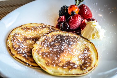 Kremalı krep çilekli ve yaban mersinli komposto ve taze krema.