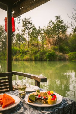 Çin 'in Hangzhou kentindeki Xixi Wetlands' da Çin gondolunda beyaz bir porselende makarna, turta ve pasta tabakları.