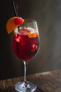 Büyük bardakta bir bardak sangria ve bir dilim portakal ve kiraz. 