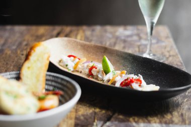 Limon suyu, arpacık soğanı, limon ve kızarmış sarımsaklı Lubina Ceviche.