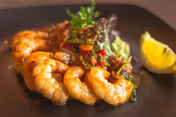 Siyah tabakta limon dilimiyle servis edilen Gambas al jillo sarımsaklı karides.