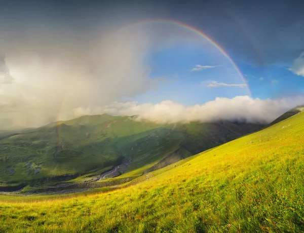 Regenbogen im Gebirgstal bei Sonnenuntergang. — Stockfoto