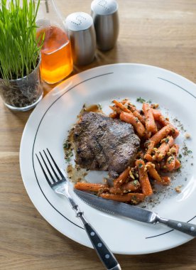 Biftek dilimlenmiş havuç beyaz tabakta ile