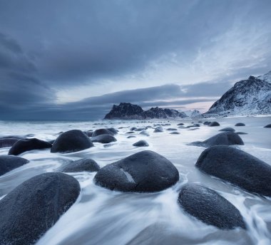 Gün batımı sırasında taşlarla deniz kıyısı. Norveç'te güzel doğal deniz manzarası