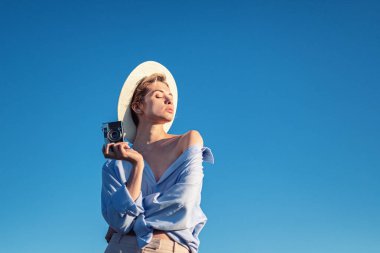 Gün batımında arka planda kamera olan genç bir kız. Kız ve kamera. Turizm ve macera. Seyahat - Resim