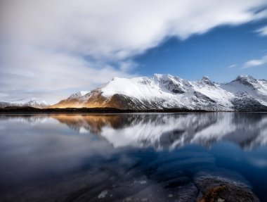 Dağlar ve gece gökyüzü, Lofoten adaları, Norveç. Su yüzeyindeki yansıma. Gece gökyüzü olan kış manzarası. Uzun pozlu çekim. Norveç yolculuğu - görüntü