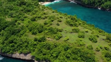 Denizde ve kayalarda hava manzarası. Turkuaz su arka planı. Havadan gelen yaz deniz manzarası. Kelingking plajı, Nusa Penida, Bali, Endonezya. Seyahat videosu