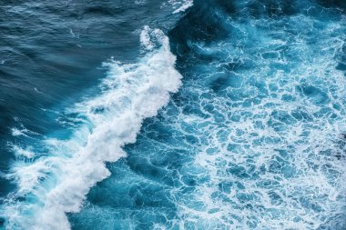 Arka plan olarak dalgalar ve mavi su. Okyanus yüzeyindeki yüksek kayaların görüntüsü. Doğal yaz deniz manzarası. Su altyapısı. Bali, Endonezya